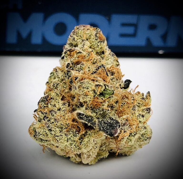 gorgeous dense bud of wedding cake strain flower in front of harvest company packaging