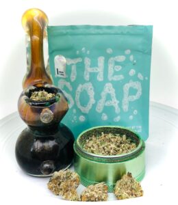sherlock pipe and the soap strain with culta ziplock in background and grinder filled with shake in foreground